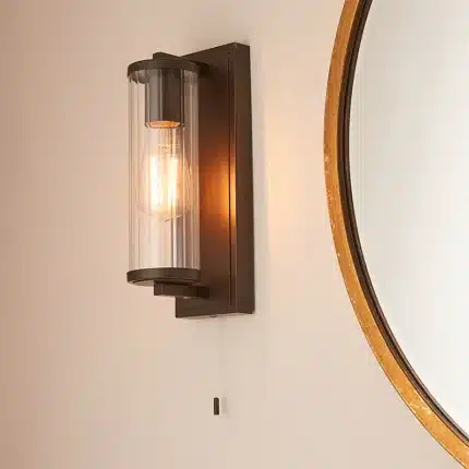 Bathroom wall light in dark bronze finish with clear glass shade