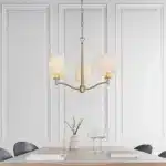Matt antique brass pendant light with vintage white shades above dining table