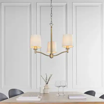 Matt antique brass pendant light with vintage white shades above dining table