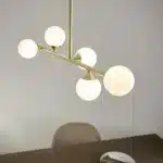 Satin brass linear pendant light with gloss opal glass shades close up