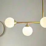 Satin brass linear pendant light with gloss opal glass shades side view
