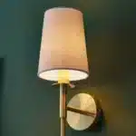 Satin brass wall light with vintage white fabric shade close up