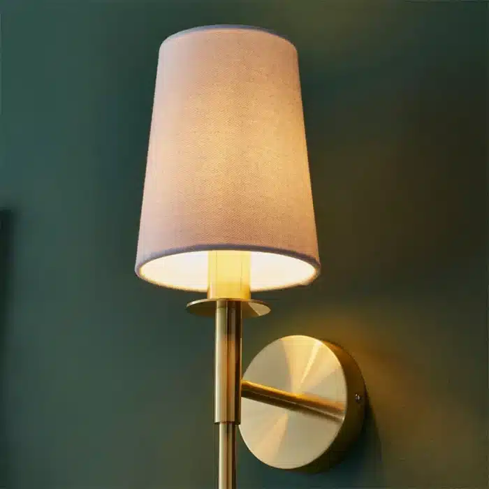 Satin brass wall light with vintage white fabric shade close up